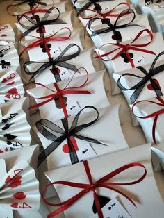 many white packages wrapped in red and black ribbon with bows on them are lined up