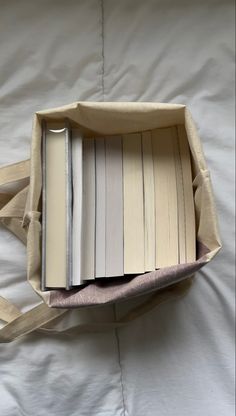 an open book in a bag sitting on top of a bed