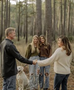 a group of people standing next to each other in the woods with a dog on a leash