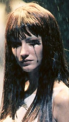 a woman with long hair and piercings on her face is standing in the rain