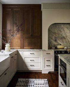 a kitchen with marble counter tops and wooden cabinets, along with an area rug on the floor