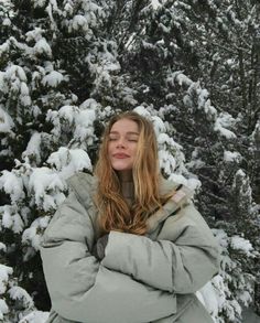 a woman standing in front of snow covered trees