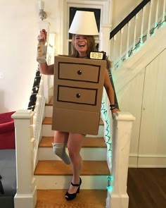 a woman is dressed as a cardboard box with a lamp on her head