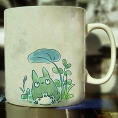 a coffee mug with an image of a green monster on it's side sitting on a table