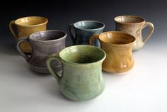 five different colored mugs lined up on a table