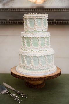 a three tiered cake sitting on top of a wooden table next to utensils