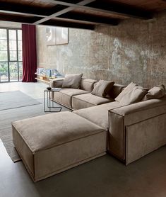 a living room with a large sectional couch and coffee table in the corner, next to an open window