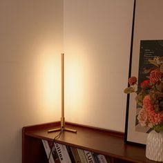 a lamp that is on top of a book shelf next to a vase with flowers