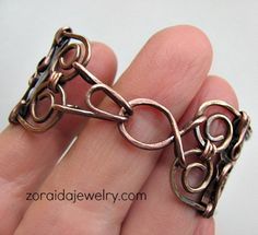 a hand holding a piece of metal that looks like a chain with links attached to it