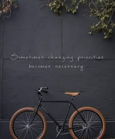 a bicycle leaning against a black wall with the words sometimes changing priorevities becomes necessary