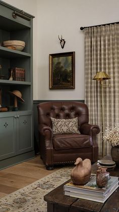 a living room filled with furniture next to a book shelf and window covered in curtains