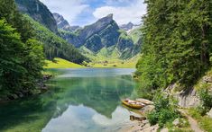 there is a boat that is sitting on the shore of this lake in the mountains