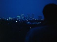 a man standing in front of a city skyline at night