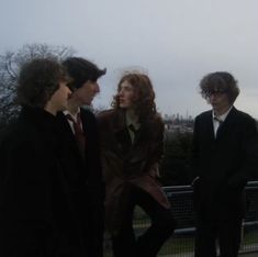 three people standing next to each other in front of a fence and cityscape