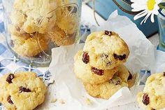 three cookies are stacked on top of each other in front of a jar filled with dried cherries