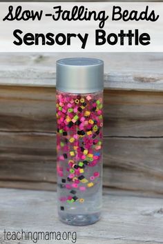 a bottle filled with colorful beads sitting on top of a wooden table