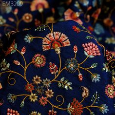 the blue fabric has colorful flowers and leaves on it's side, as well as an intricately designed design