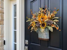 a bucket filled with sunflowers and other flowers sitting on the front door sill