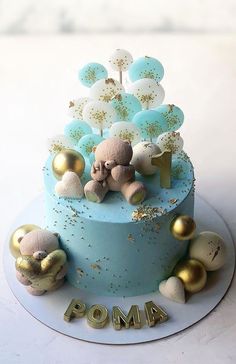 a blue cake with gold decorations and teddy bears on the top is for poma