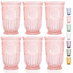 six pink glass tumblers are lined up against a white background, each with an ornate design