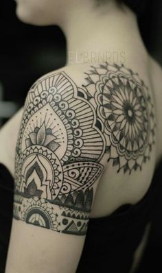 the back of a woman's shoulder with an intricate tattoo design on her arm