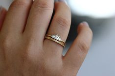 a woman's hand wearing a gold ring with two baguettes on it