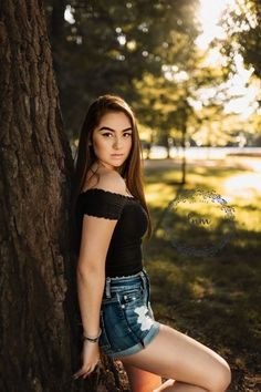 a beautiful young woman leaning against a tree