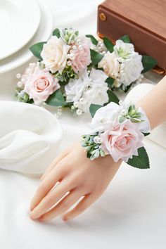 the bride's wrist is adorned with pink and white flowers