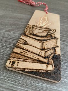 a wooden bookmark with a cup of coffee on top of some books and a red string