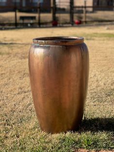 a large metal vase sitting on top of a grass covered field