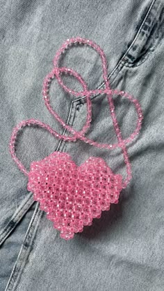 a pink heart shaped brooch sitting on top of a pair of jeans