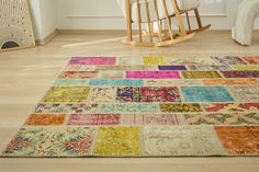 a multicolored patchwork rug with wooden rocking chair in the background