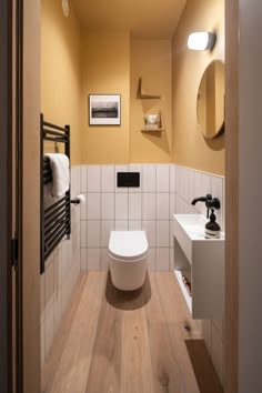 a white toilet sitting in a bathroom next to a sink and wooden counter top under a mirror