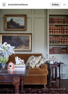 a living room filled with furniture and bookshelves next to a painting on the wall