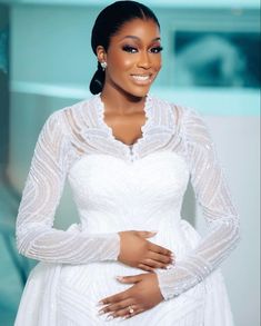 a woman in a white dress posing for the camera with her hands on her stomach