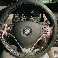 a steering wheel with pink bows tied around the spokes and center console in a car