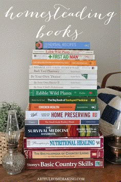 a stack of books sitting on top of a wooden table next to a vase and lamp