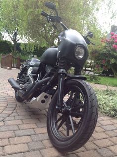 a black motorcycle parked on top of a brick road