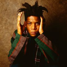 a young man with dreadlocks holding his head