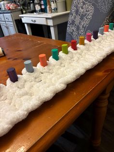 a wooden table topped with lots of white snow covered in colorful cups and blocks on top of it