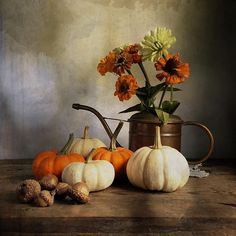 a still life with flowers and pumpkins on a table