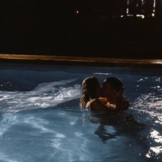 two people in a swimming pool with their backs to each other and one person kissing