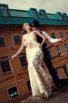 a man and woman are posing for a photo in front of an old brick building