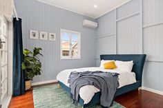 a bed sitting on top of a wooden floor next to a blue wall and window