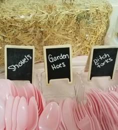 there are some pink plates and spoons on display at the table with straw bales in the background