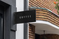 a sign on the side of a building that says coffee next to a window with flowers hanging from it