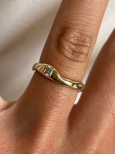 a woman's hand wearing a gold ring with two diamonds on the middle of it