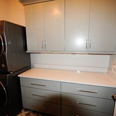 a kitchen with white cabinets and gray drawers next to a washer and dryer