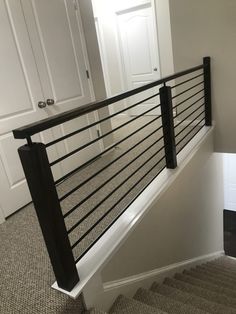 a stair case with black railing and white door