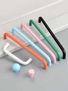 four different colored plastic handles on a white wall next to an object that looks like a ball